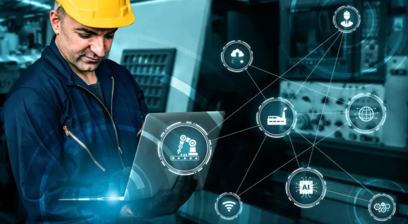 Indústria 4.0: Sensores e IoT Aplicados à Manutenção Preditiva. Engenheiro com capacete em ambiente industrial, monitorando sistemas em notebook com ícones de sensores e dados conectados por rede e hologramas digitais.
