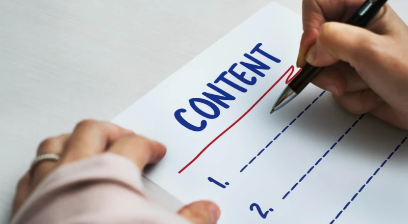 Conteúdo Original vs Conteúdo Genérico: Por Que a IA Despreza O Que já Existe Em Todo lugar: Pessoa escreve a palavra “CONTEÚDO ORIGINAL” em um papel com caneta, comparando conteúdo genérico e conteúdo original com linhas marcadas, enquanto outra mão segura a caneta e realiza o desenho gráfico.